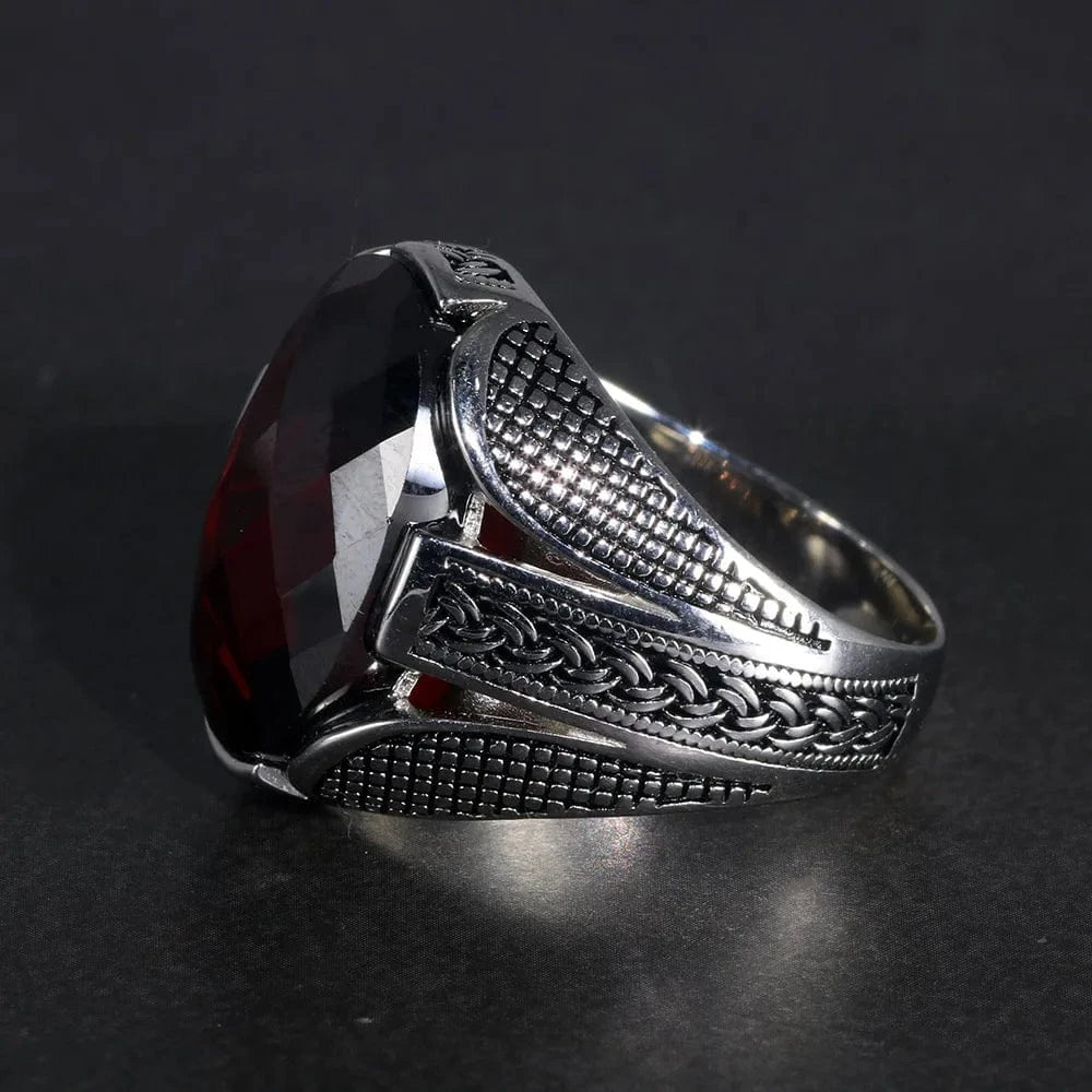 Silver ring with a prominent red stone on a dark background