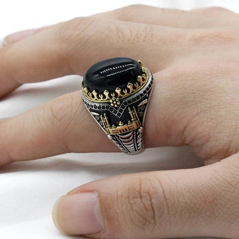 Image of Decorative ring with a black stone on a finger against a white background