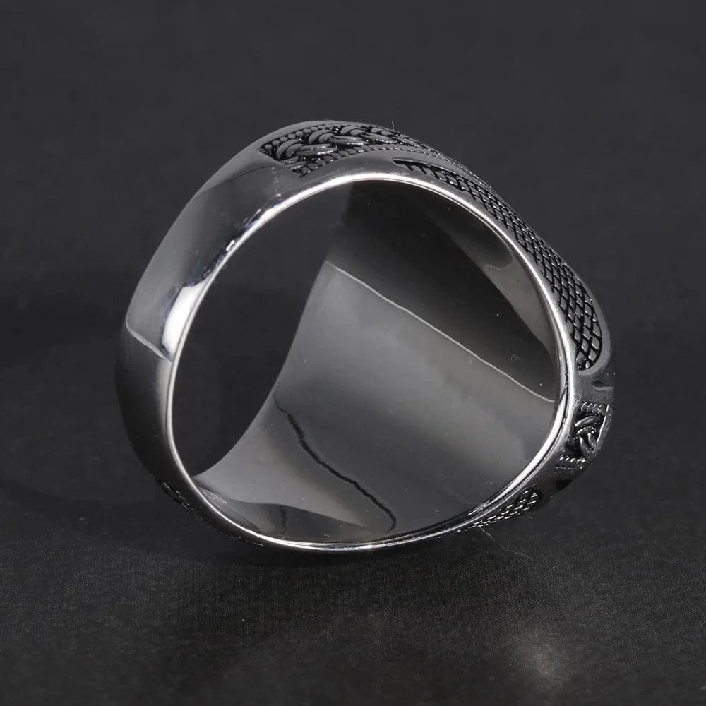Silver ring with intricate design on a dark background