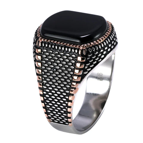 Image of Ring with black stone and metallic band on a white background