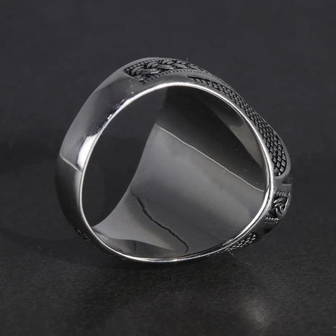 Image of Silver ring with intricate design on a dark background