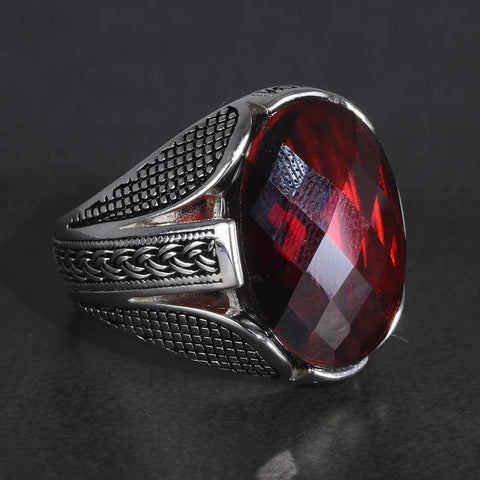 Image of Silver ring with a large red gemstone on a dark background