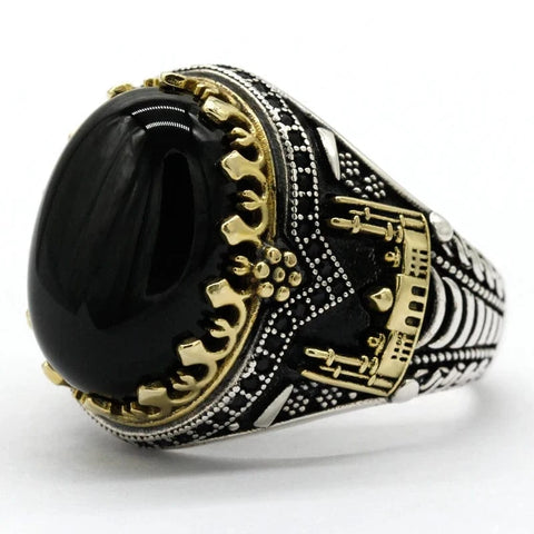 Image of Decorative ring with black gemstone and gold and silver design on a white background