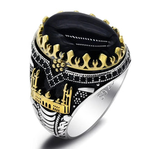 Luxury ring with black stone, gold accents, and silver band on a white background