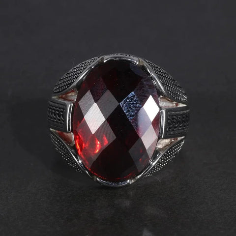Image of Silver ring with a red gemstone on a dark background