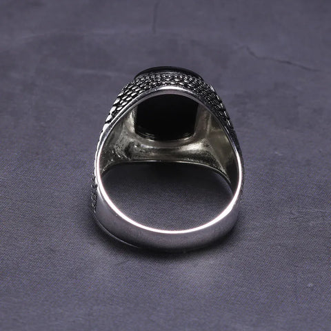 Image of Silver ring with black stone on a dark gray fabric background