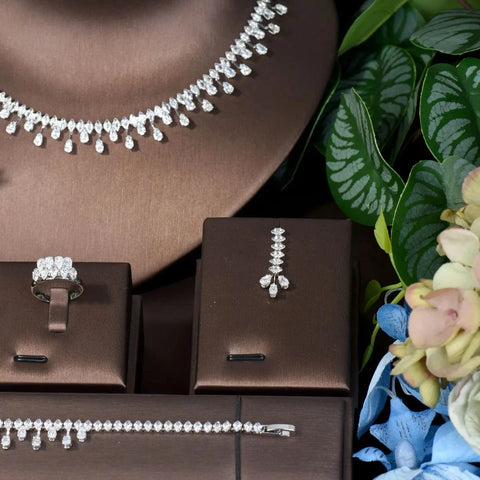 Image of Jewelry set including necklace, ring, and earrings on brown stands with a floral background.