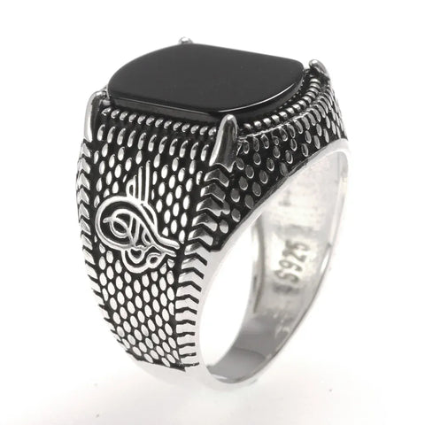 Image of Silver ring with black stone and intricate design on a white background